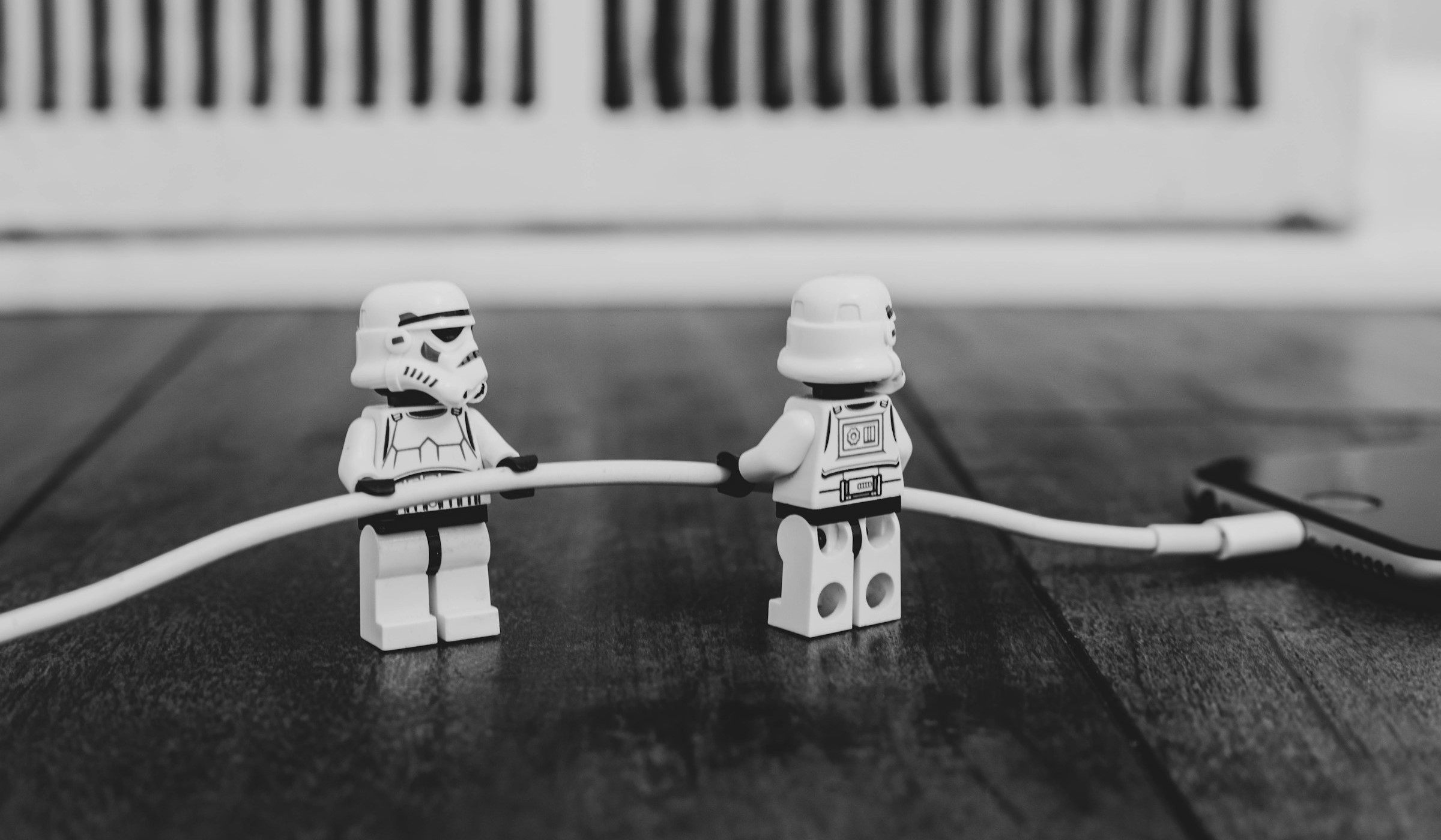 Two LEGO Stormtroopers plugging a phone charger into a phone.